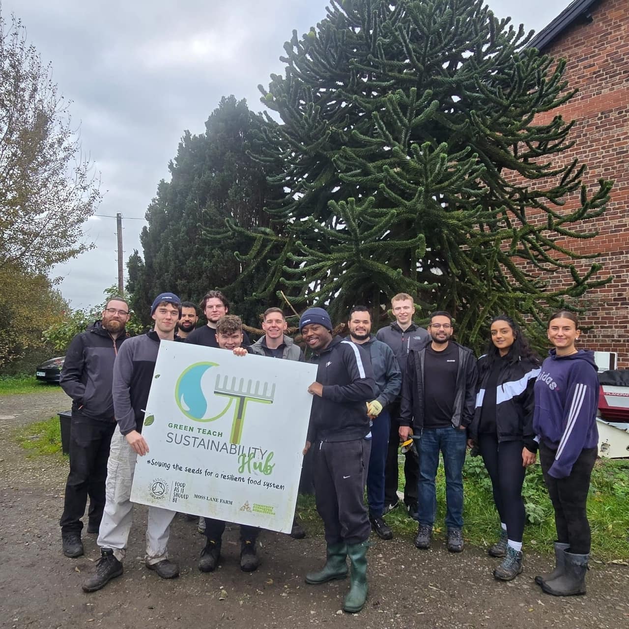The Anaplan volunteers with the Green Teach Sustainability Hub sign, in front of the monkey puzzle tree